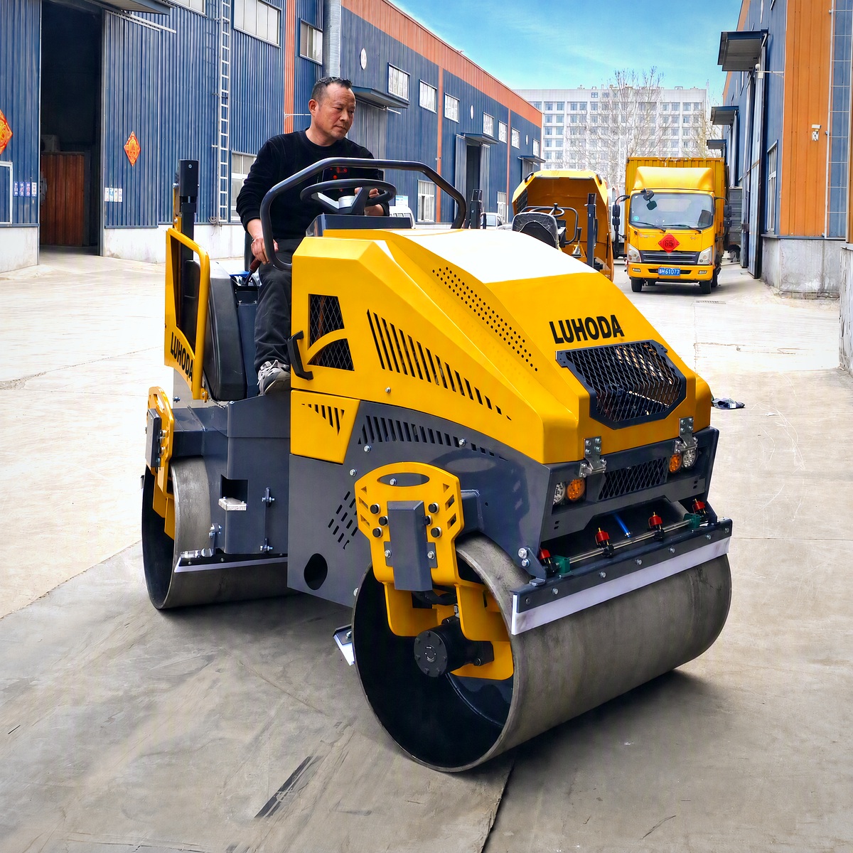 LHD-YL800S ride-on tandem vibratory road roller with LUHODA decal, driven by its operator on the paved yard of Shandong Luhongda Machinery under a clear sky